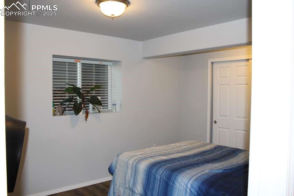 Bedroom with dark wood finished floors and a closet