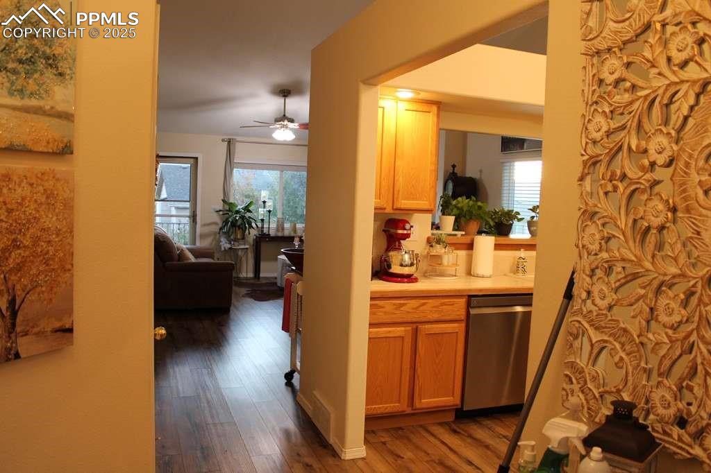 Kitchen featuring light countertops, dark wood-style floors, stainless steel dishwasher, and a ceiling fan