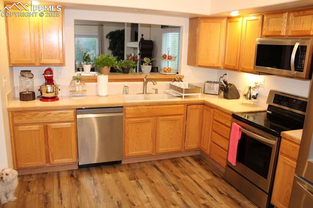 Kitchen with appliances with stainless steel finishes, light countertops, light wood-type flooring, and plenty of natural light