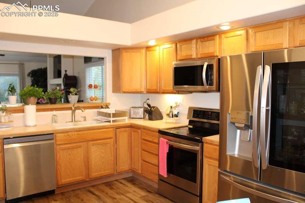 Kitchen featuring stainless steel appliances, light countertops, light brown cabinets, and light wood finished floors