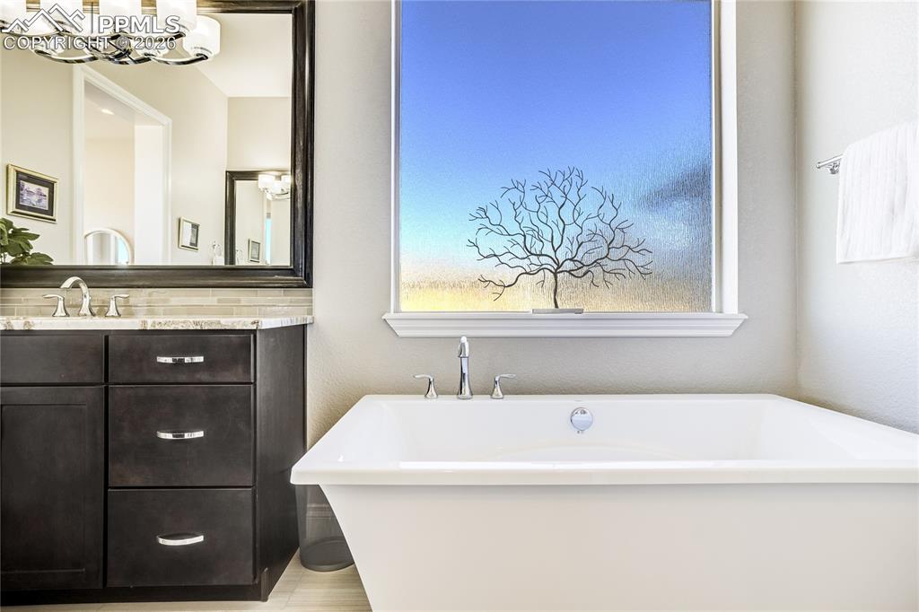 Spa-inspired bath with freestanding soaking tub, dual vanities and zero-entry frameless mud-set shower.