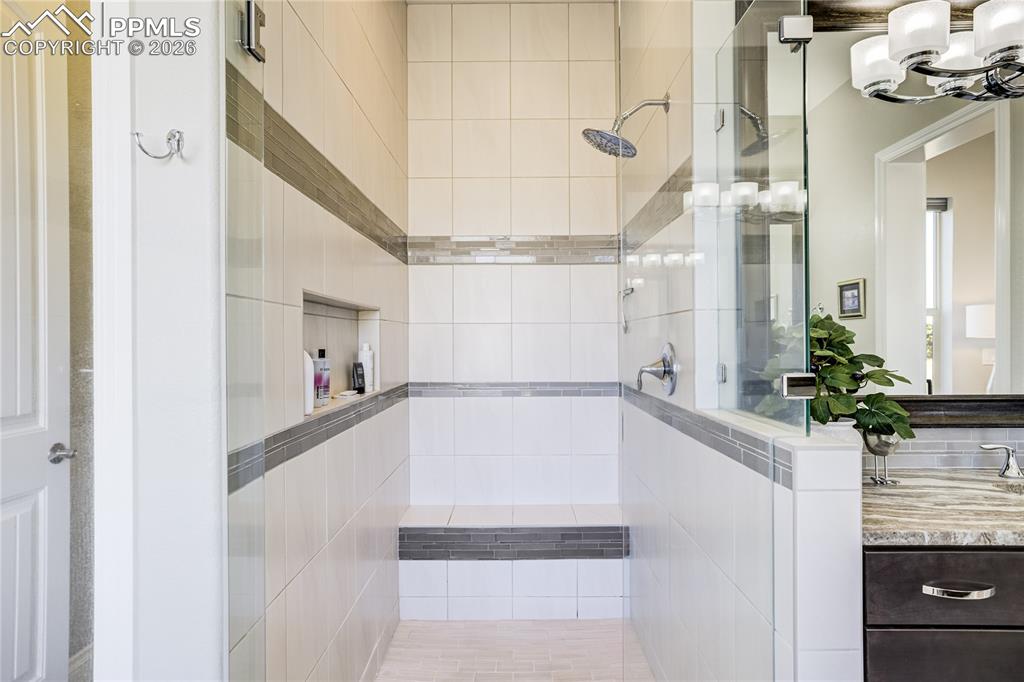 Spa-inspired bath with freestanding soaking tub, dual vanities and zero-entry frameless mud-set shower.