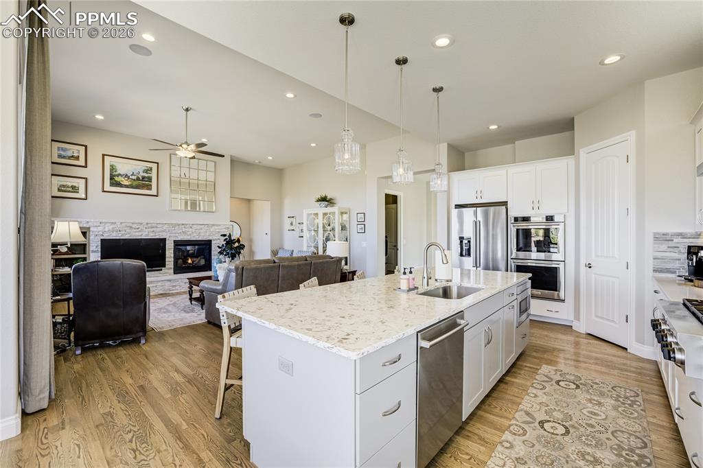 Light-filled great room anchored by a stone-surround gas fireplace and integrated speakers, framed by layered pond + mountain views.
