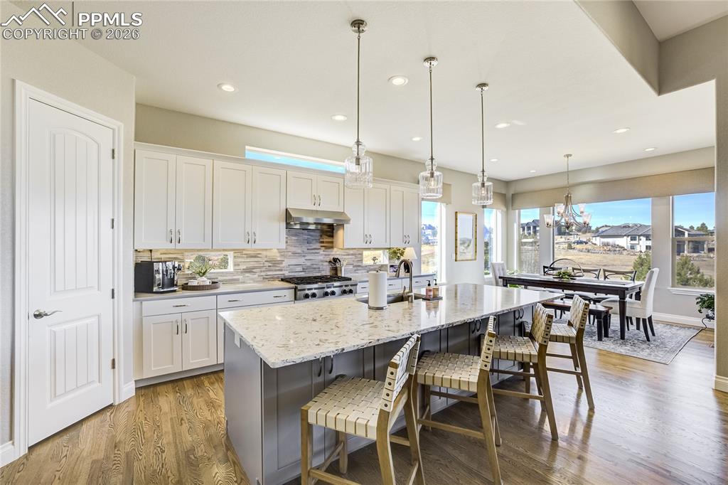 Chef-oriented kitchen featuring stainless steel double wall ovens, gas cooktop, soft-close cabinetry and expansive island with seating + storage.