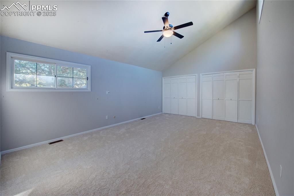 Additional living space featuring a ceiling fan, carpet flooring, and lofted ceiling