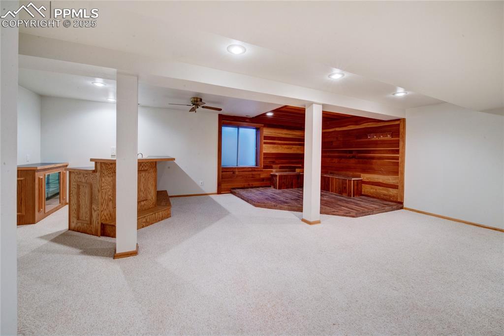Finished below grade area with wood walls, wet bar, recessed lighting, and carpet