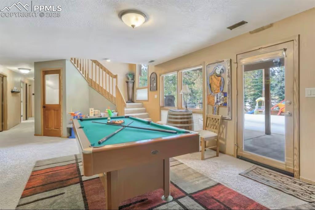 Recreation room with pool table, carpet flooring, and a textured ceiling