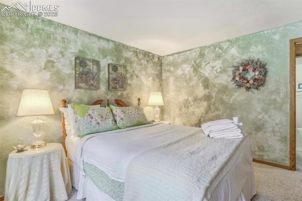 Bedroom featuring wallpapered walls and light carpet