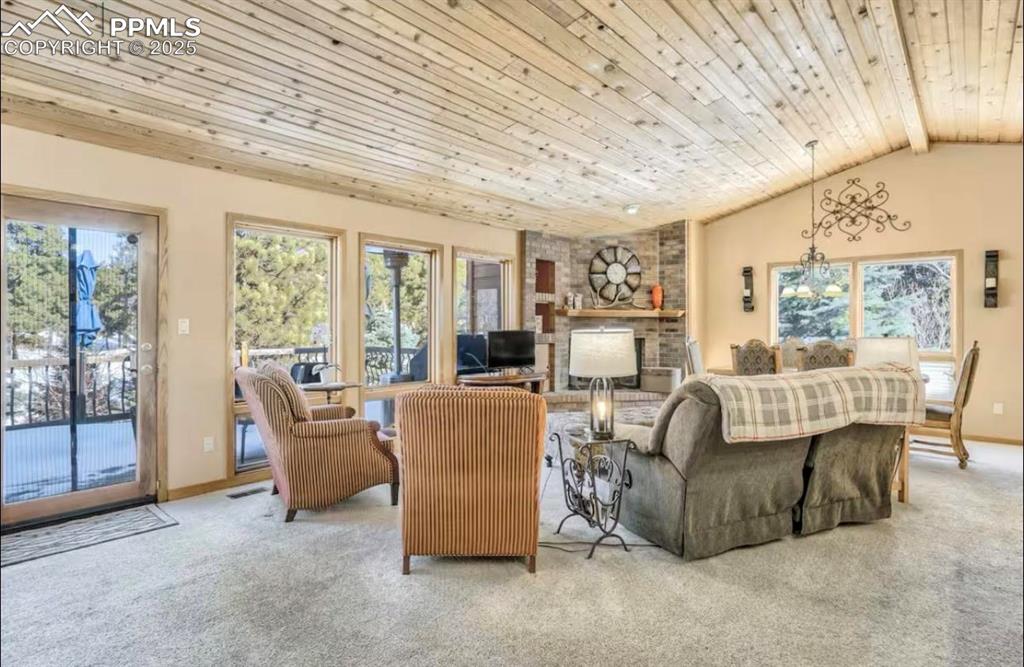 Carpeted living room with wooden ceiling, lofted ceiling, and a fireplace