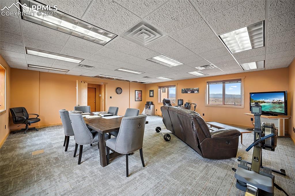 Carpeted dining room with a drop ceiling and baseboards