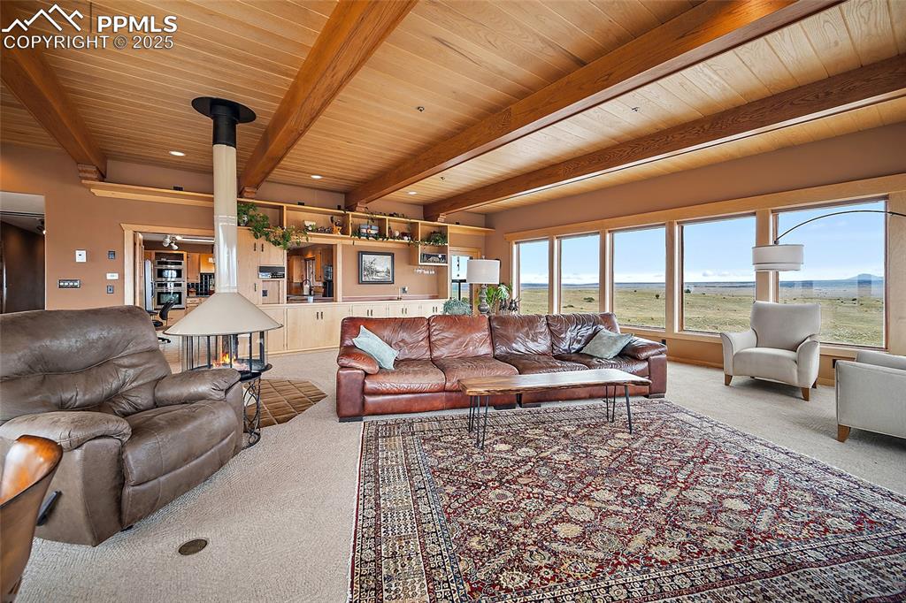 Living area with light colored carpet and a wooden ceiling with exposed beams