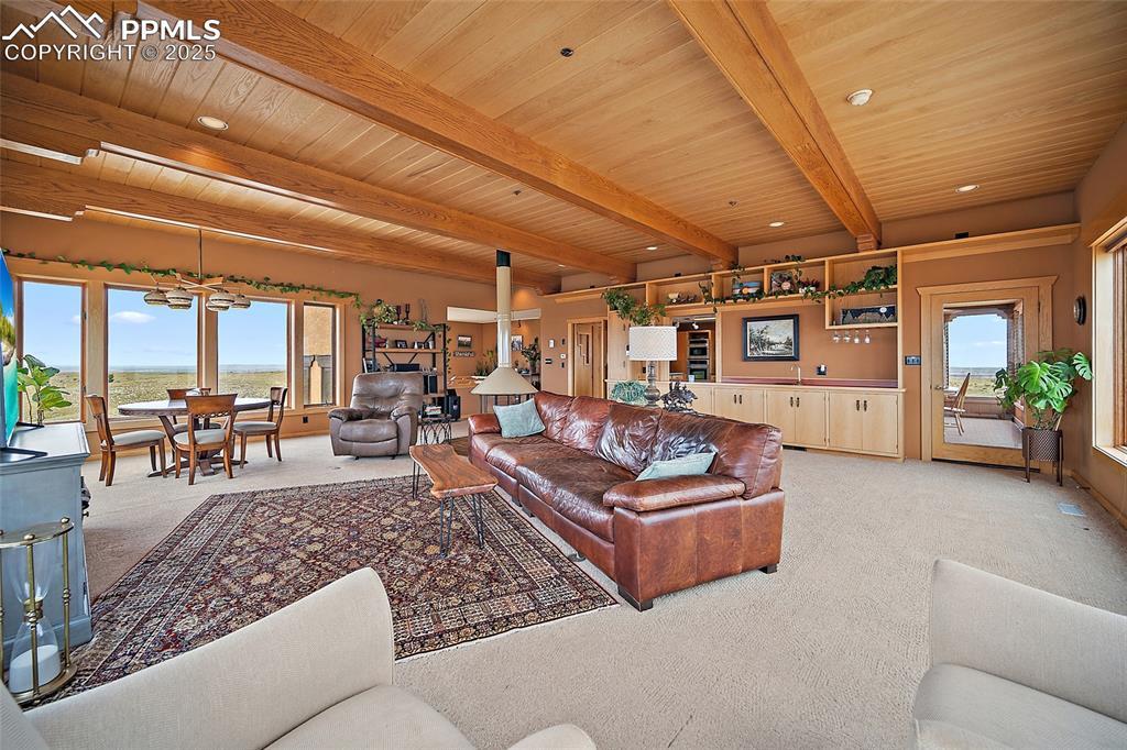 Living area with light colored carpet and a wood ceiling with exposed beams