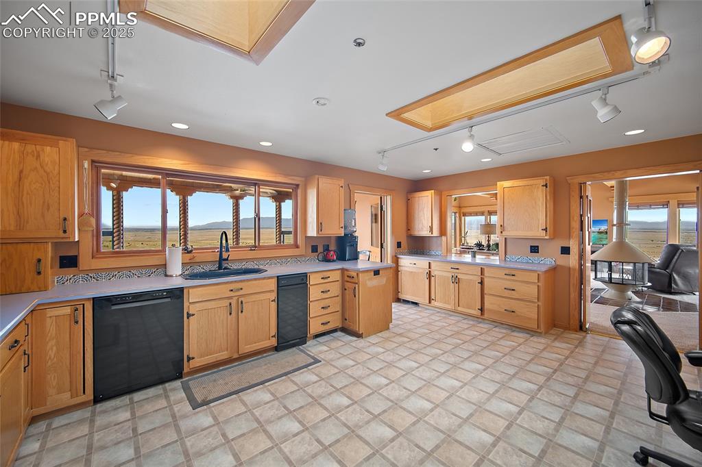 Kitchen with rail lighting, black dishwasher, and light countertops