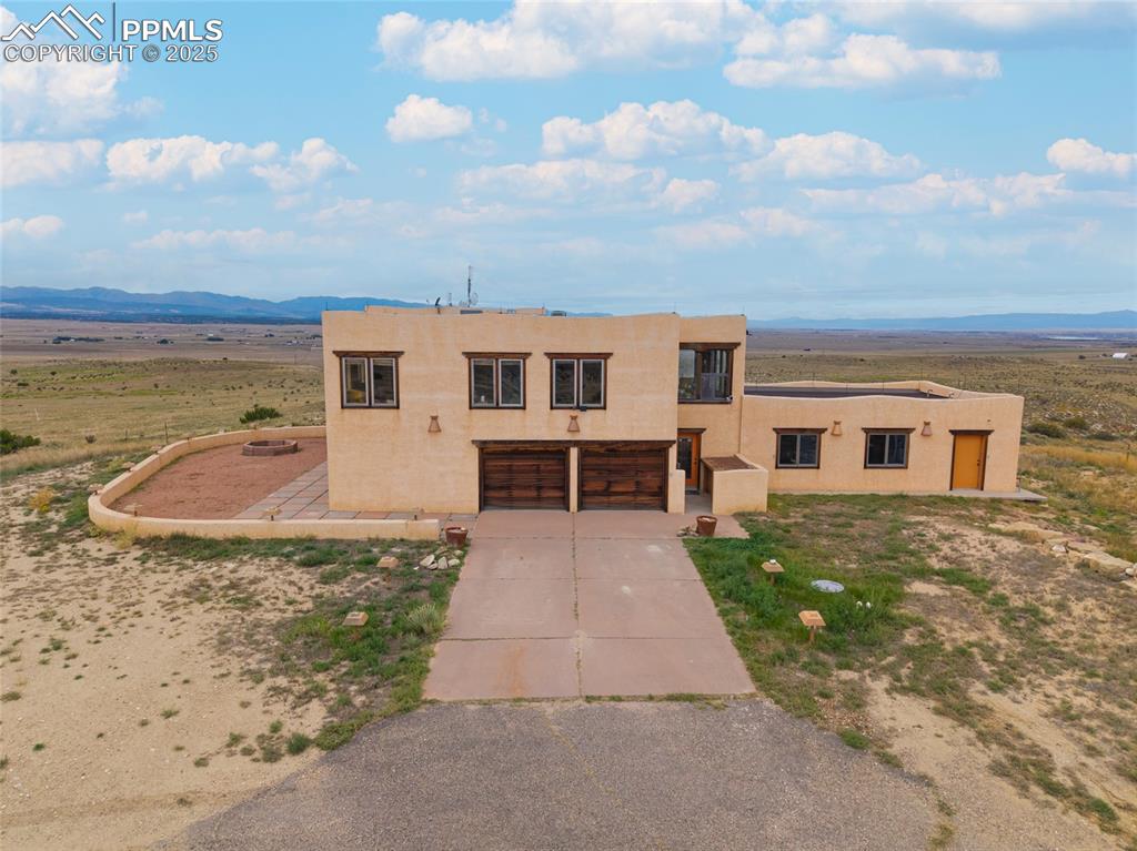 Pueblo revival-style home with stucco siding, concrete driveway, a mountain view, and an attached garage