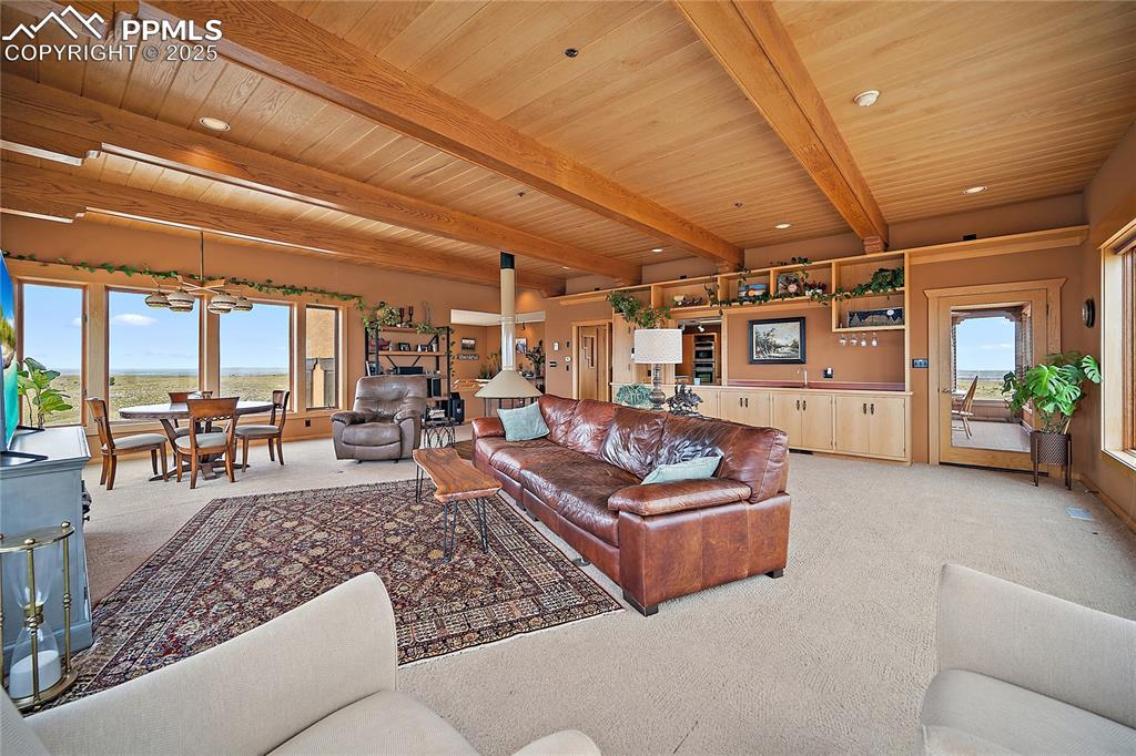 Living room with light colored carpet and a wooden ceiling with exposed beams