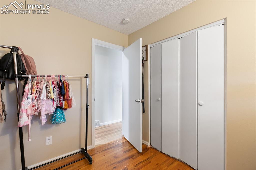 Bedroom featuring a textured ceiling, light wood-style floors, and a closet