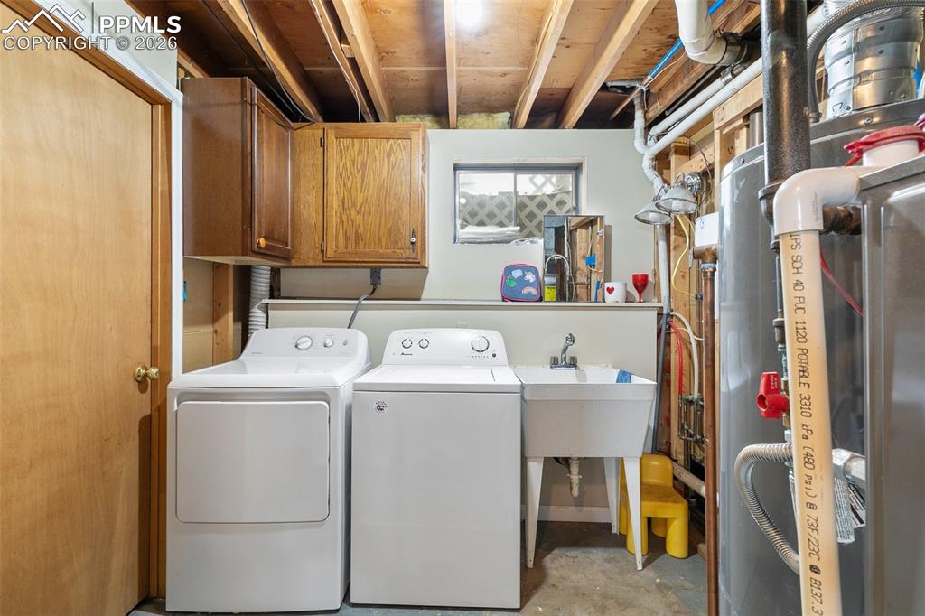 Laundry area with cabinet space, unfinished concrete floors, washer and dryer, and heating unit