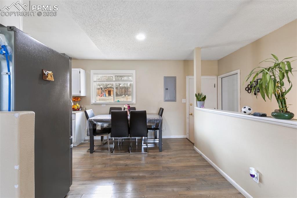 Dining area with dark wood-type flooring, electric panel, a textured ceiling, and recessed lighting