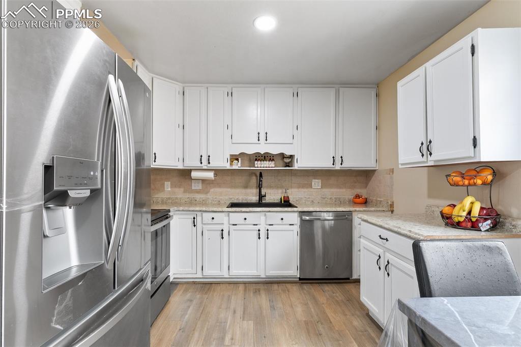 Kitchen featuring stainless steel appliances, white cabinets, and light wood-type flooring