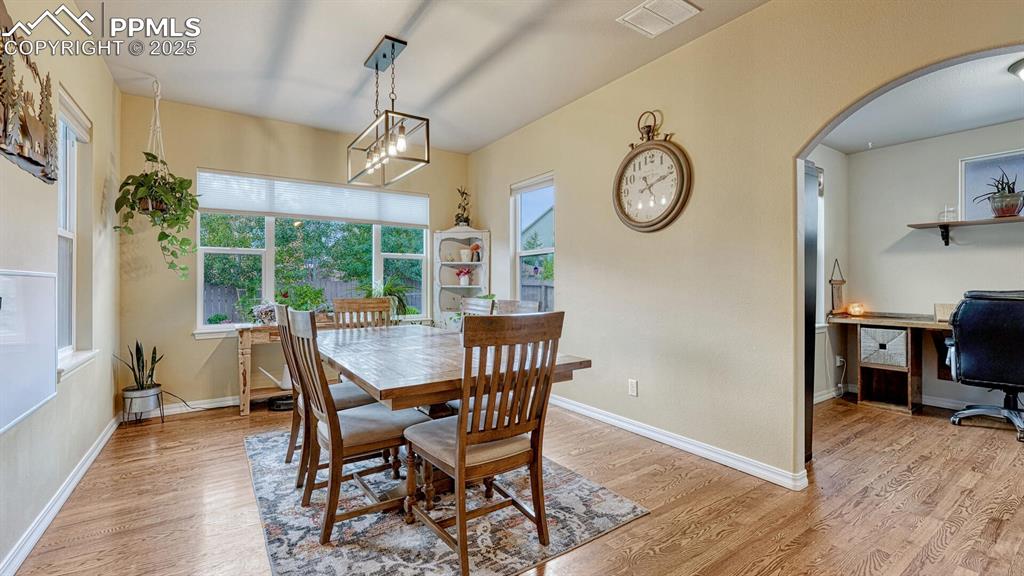 Dining space with plenty of natural light, light wood finished floors, and arched walkways