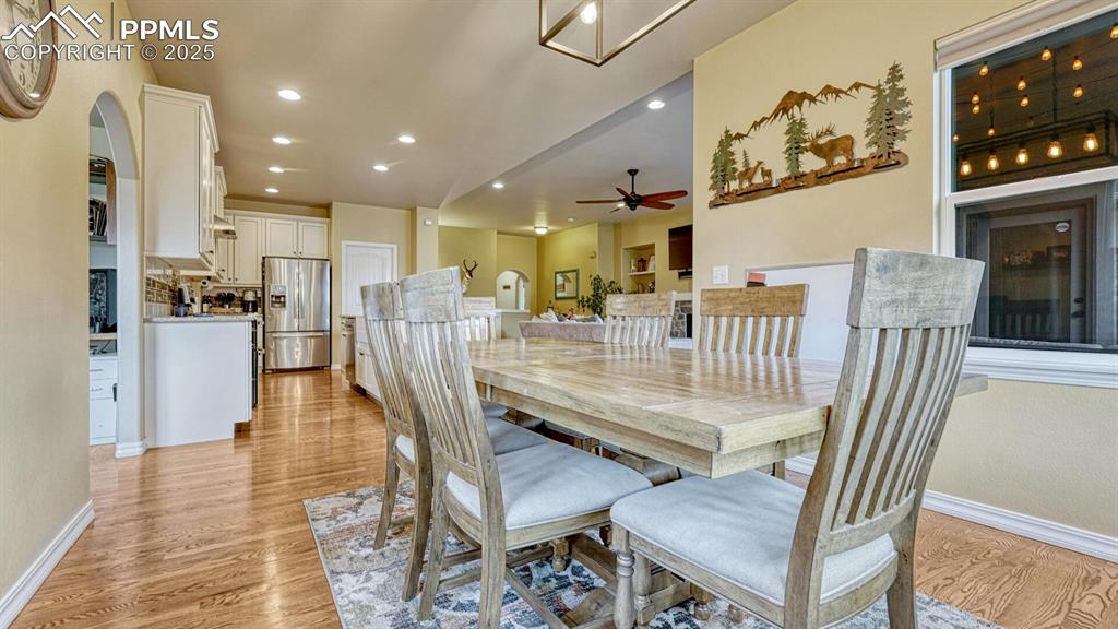 Dining space featuring light wood-style floors, recessed lighting, arched walkways, and ceiling fan
