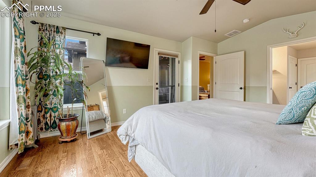 Bedroom with light wood-style floors, vaulted ceiling, and ceiling fan
