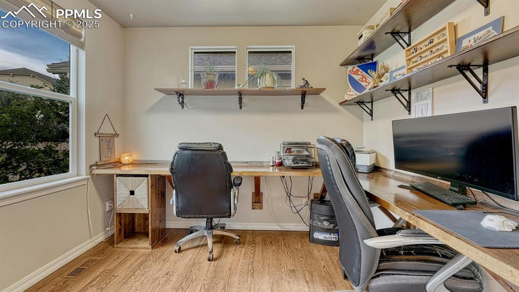 Home office with light wood-style floors and healthy amount of natural light