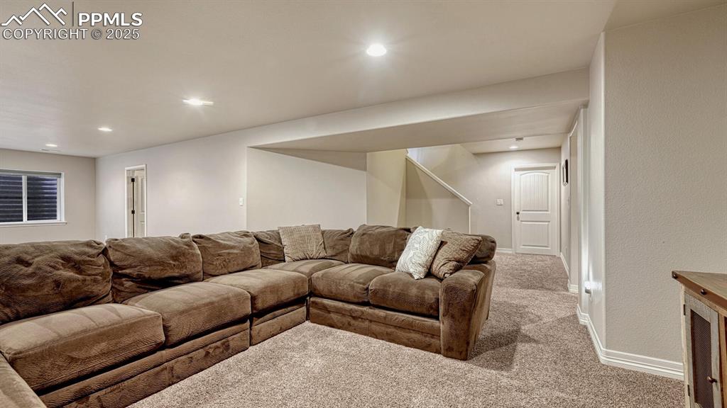 Carpeted living area with baseboards and recessed lighting