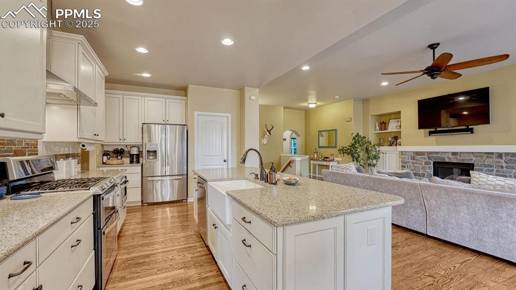 Kitchen featuring appliances with stainless steel finishes, white cabinetry, light wood finished floors, recessed lighting, and open floor plan