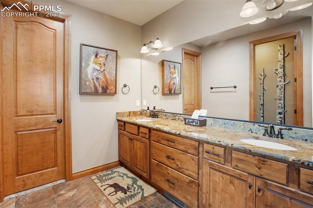 Bathroom featuring double vanity, baseboards, and a sink