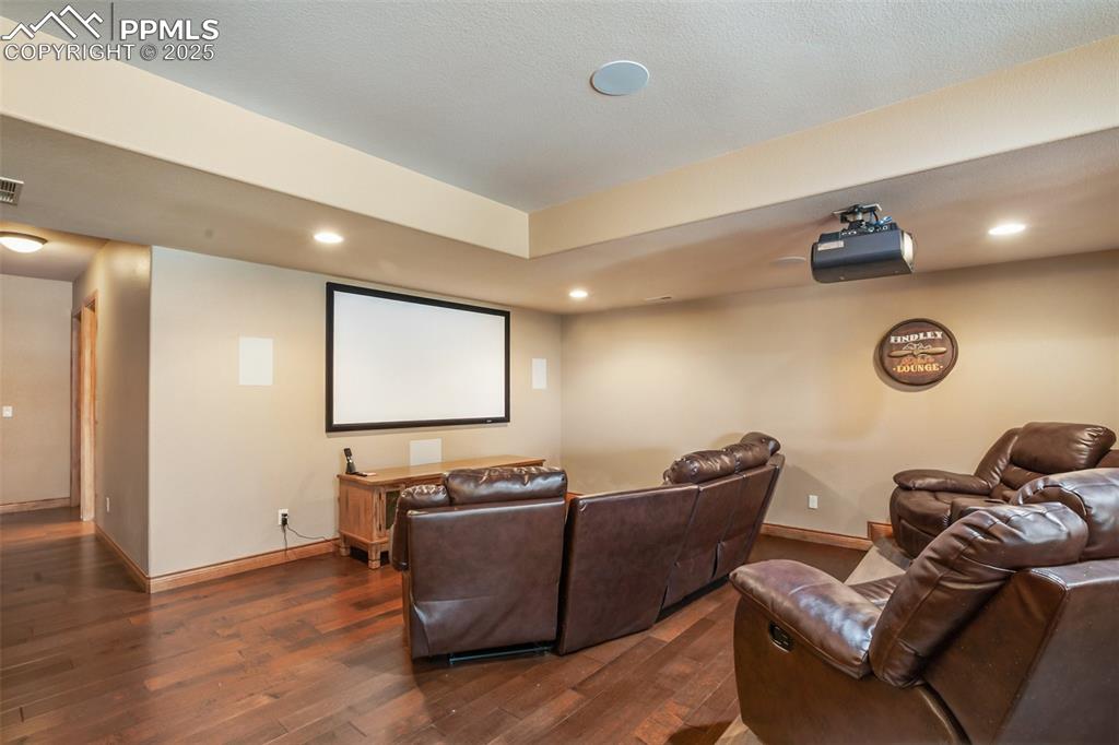 Cinema room featuring visible vents, baseboards, and dark wood-style flooring