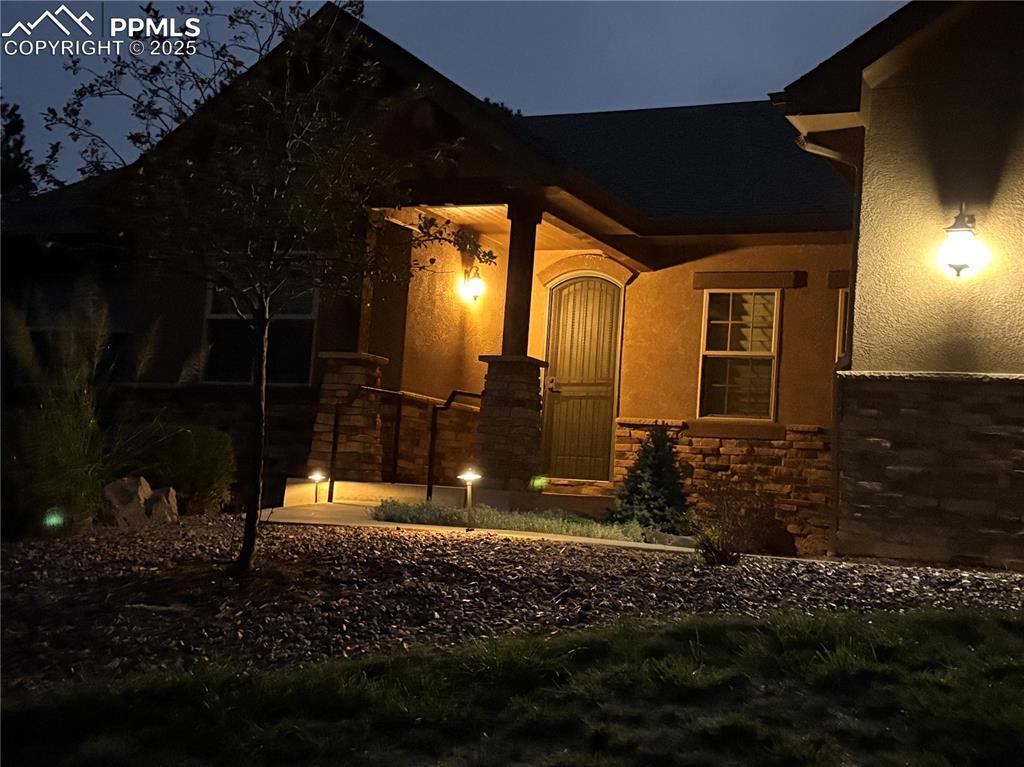 View of front of property with stone siding, covered porch, and stucco siding