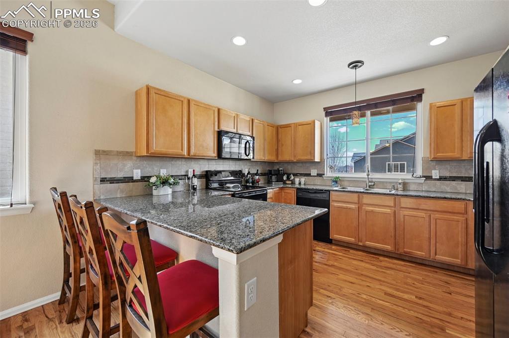 Stunning open kitchen featuring granite countertops, a large breakfast bar, ample cabinets, a brand-new dishwasher, and breathtaking mountain views.