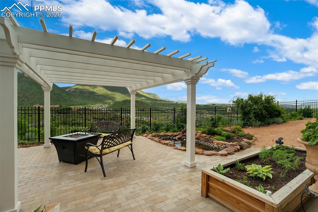 Fully landscaped back yard with stone patio, pergola, and pond