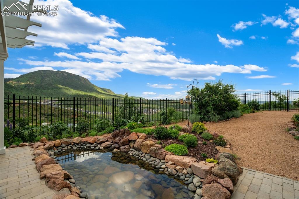 Fully landscaped back yard with stone patio, pergola, and pond
