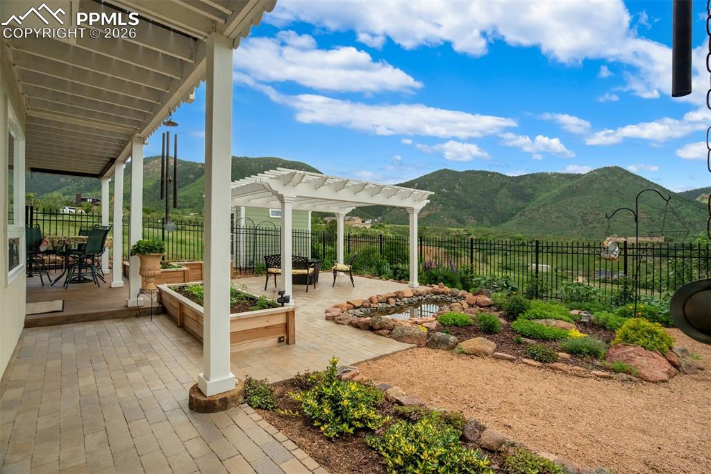 Fully landscaped back yard with stone patio, pergola, and pond