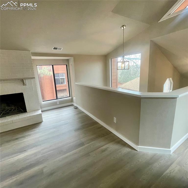 Great Room featuring new flooring, a brick fireplace & lofted ceiling