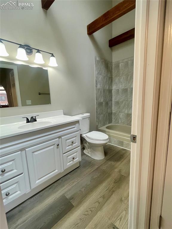 Bathroom with vanity, light wood-style floors, beam ceiling, and bathing tub / shower combination