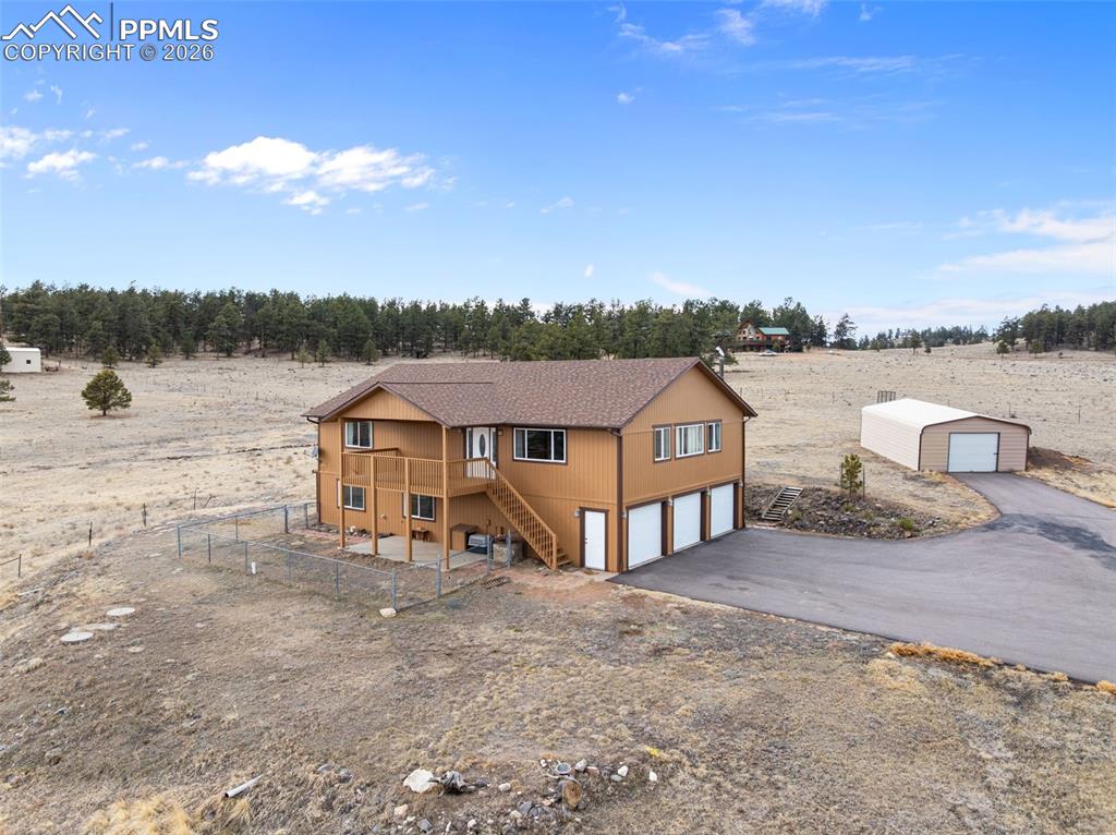 Exterior view of the home featuring fresh stain, attached garage, and large outbuilding.