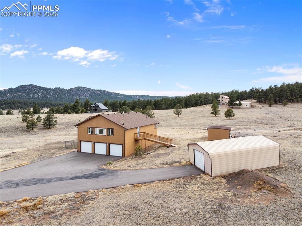 Exterior view of the home featuring fresh stain, attached garage, and large outbuilding.