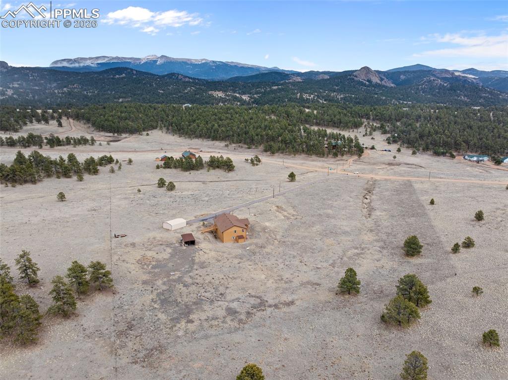 Aerial view of the property with surrounding hills and open land.