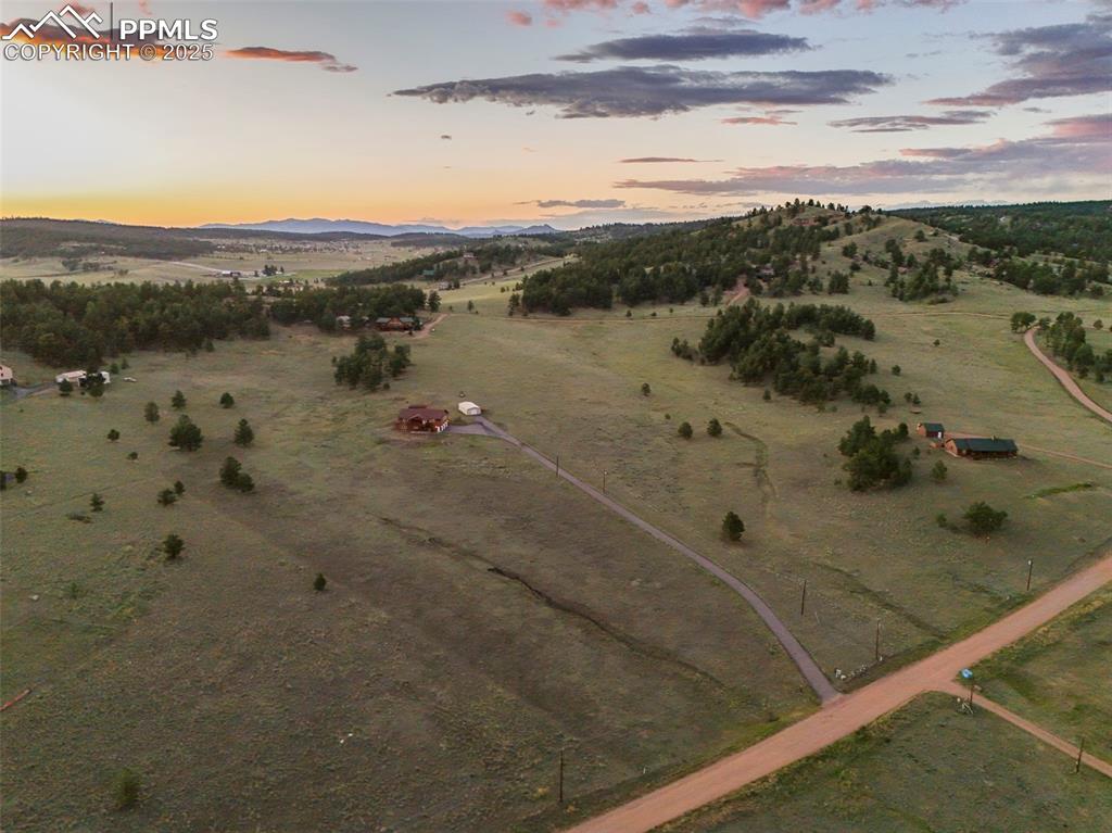 Aerial view of the property with surrounding hills and open land.