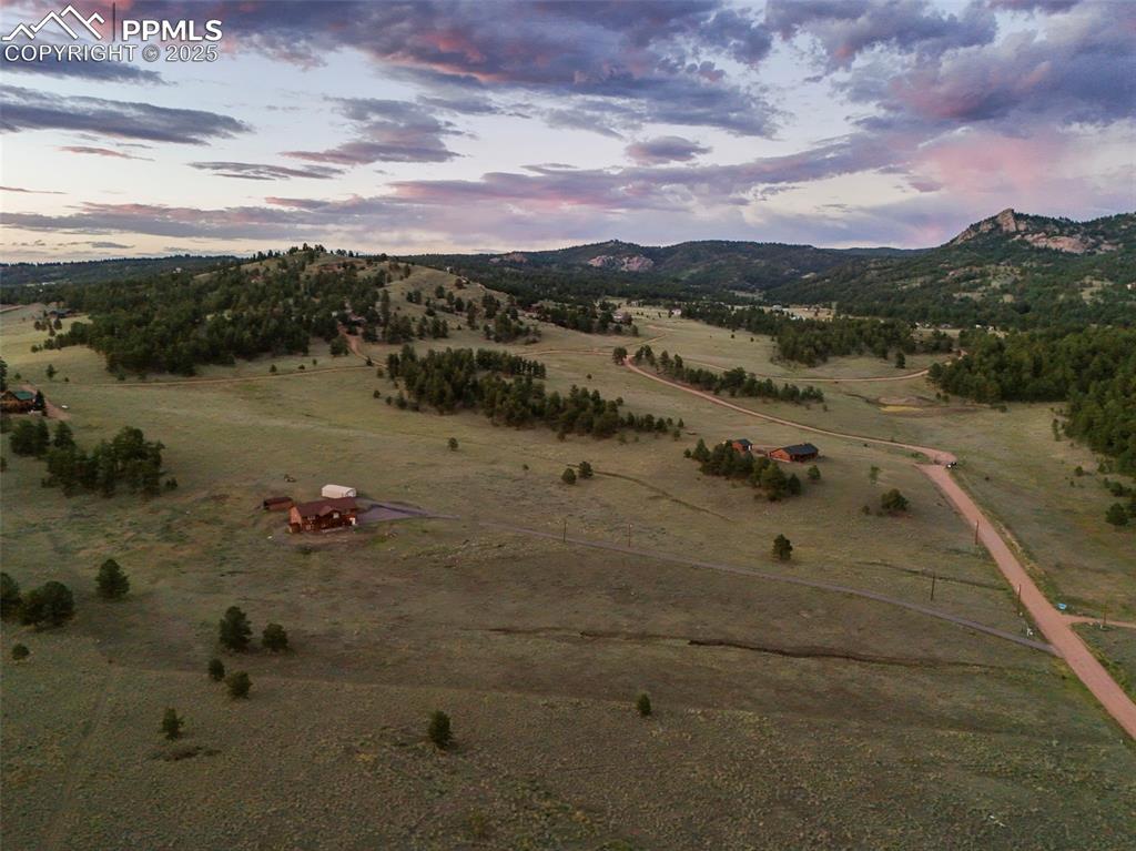 Aerial view of the property with surrounding hills and open land.