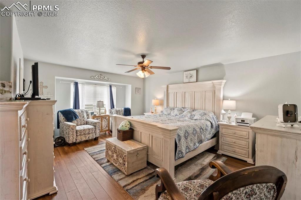 Bedroom featuring a textured ceiling, dark wood-type flooring, and a ceiling fan