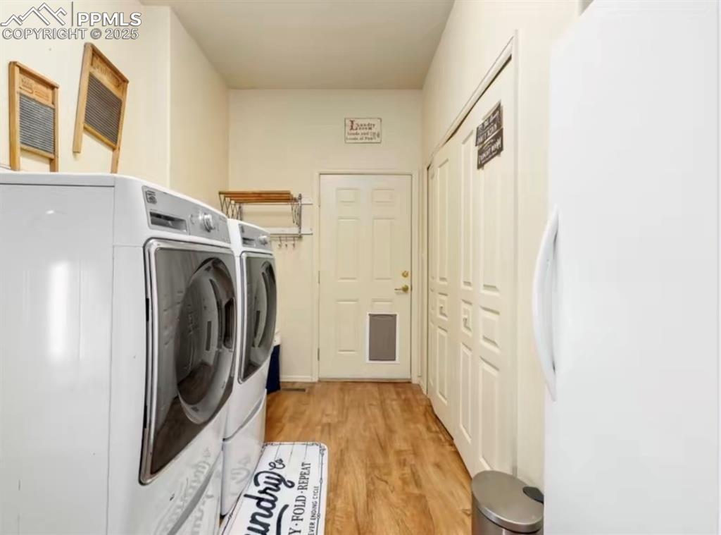 Laundry area with washing machine and dryer and light wood finished floors