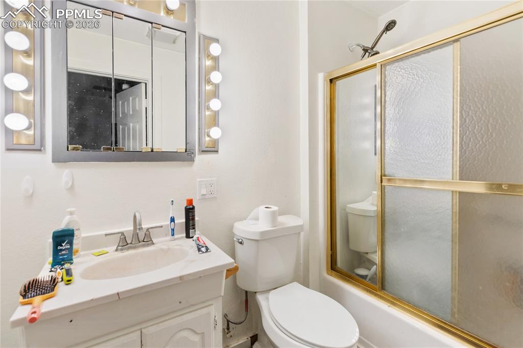 The bathroom features a vanity and a combined bath/shower with a glass door!