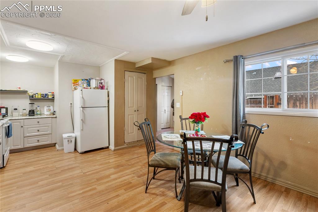The dining room has light wood-style flooring and a ceiling fan overlooking the kitchen!