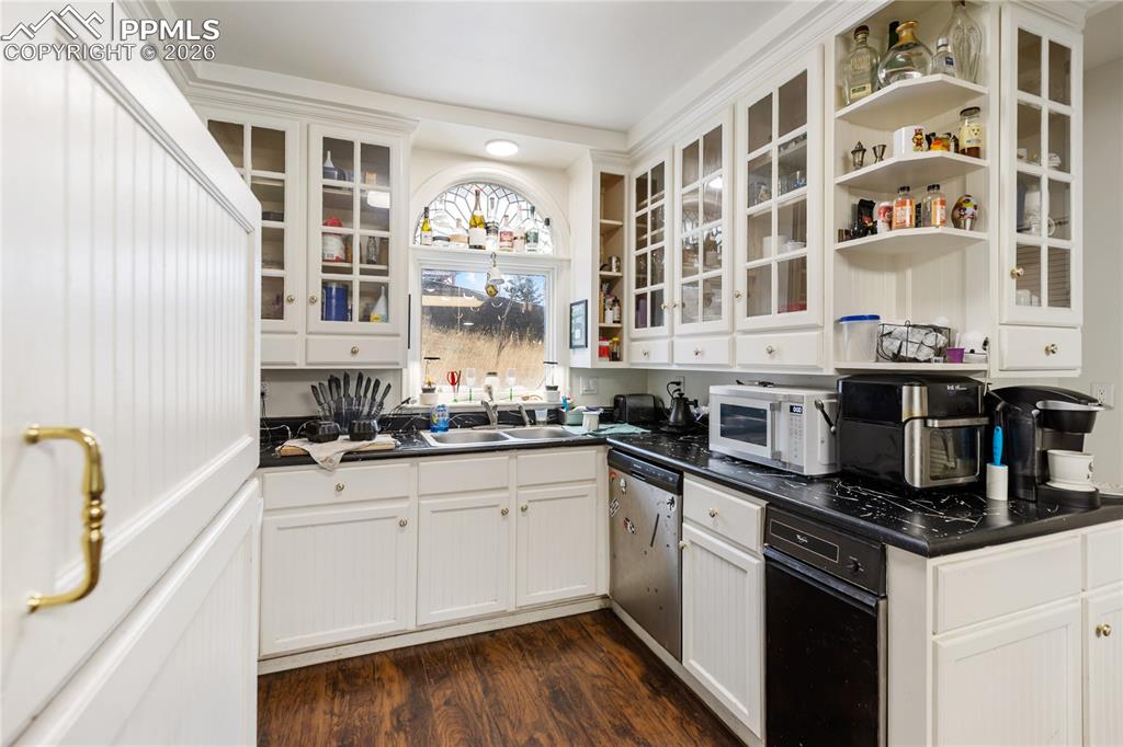 The kitchen has white glass French doored cabinetry, White appliances, and dark wood-style flooring!