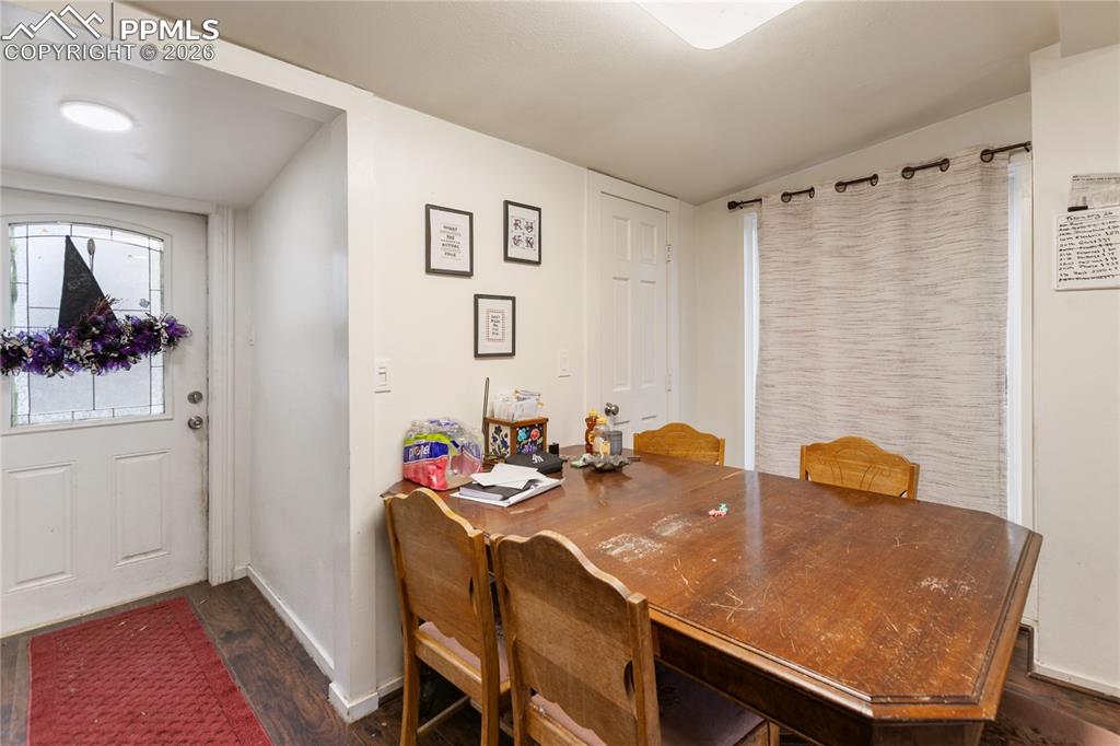 The dining area with dark wood-style floors and the entry way!