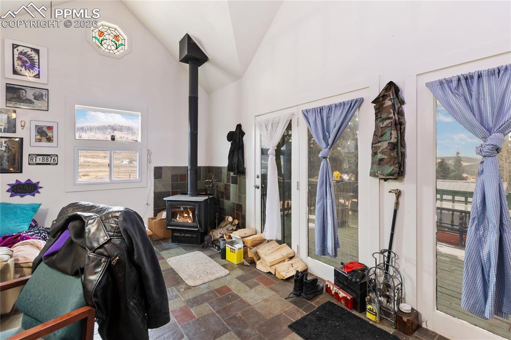 The walk-out living area has stone tile floors, a wood stove, lofted ceilings, and a stained-glass window!